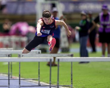 Athlete jumping over hurdles during a track event.