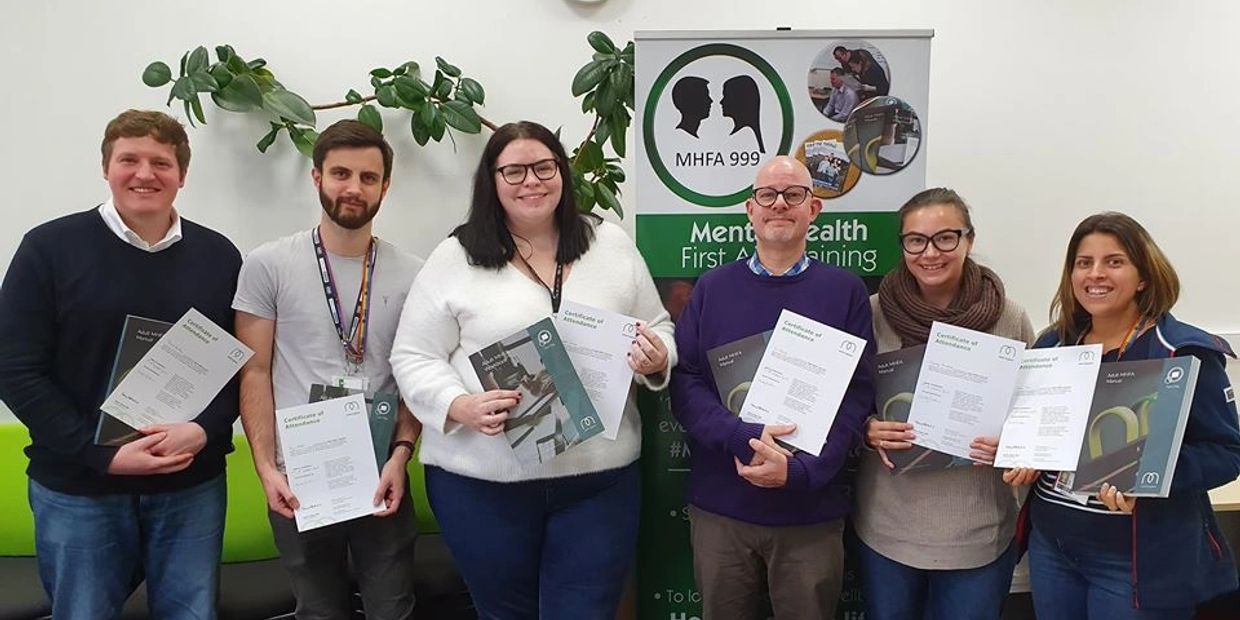 People pictured with their certificates after completing a mental health first aid course.