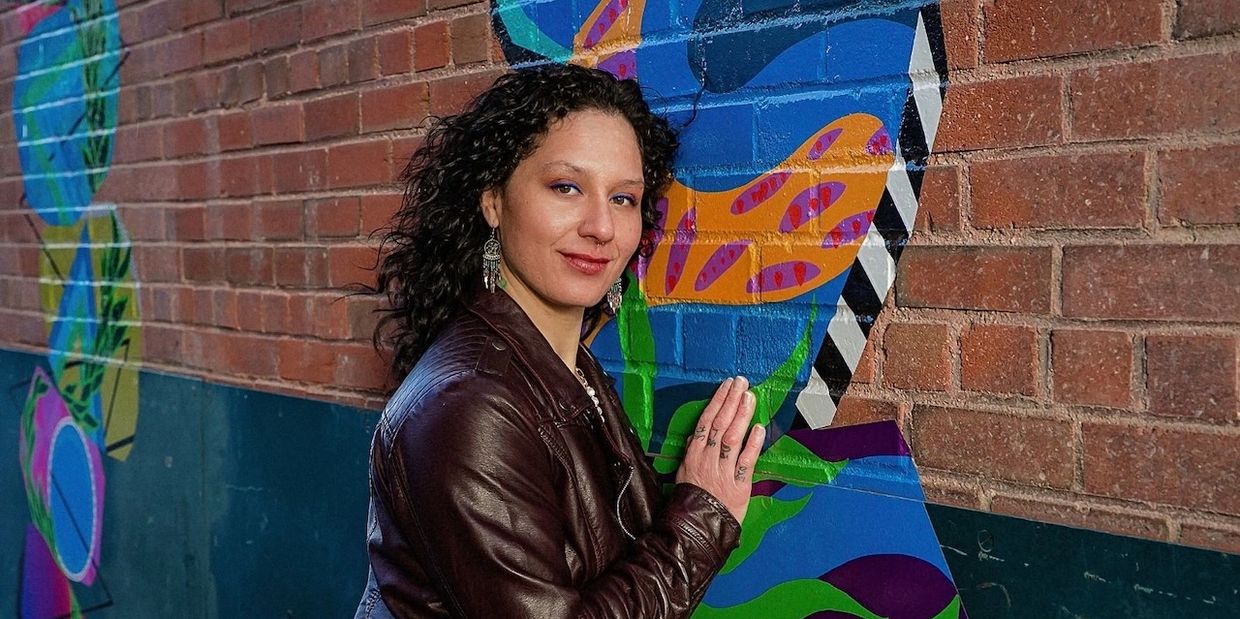 Female singing teacher smiling and standing against a wall with art