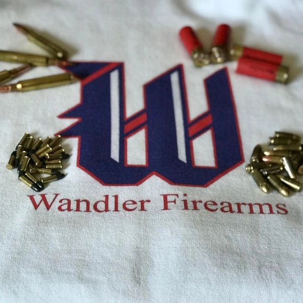 Various types of ammunition arranged around a Wandler Firearms logo on fabric.