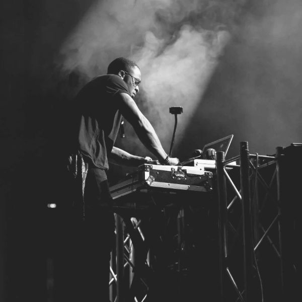 A DJ performing live on stage with dramatic lighting and smoke effects.