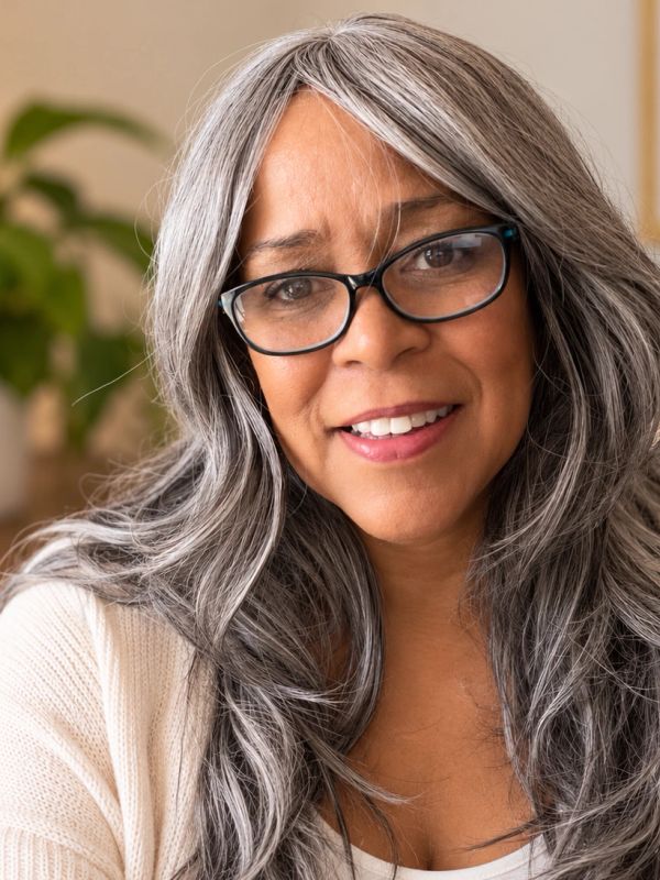 Smiling woman with gray hair and glasses.
