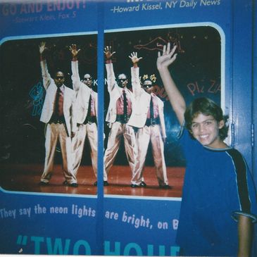 Boy mimics raised hand pose of men in poster behind him.