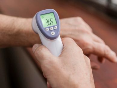 Person using a thermometer on a wrist.