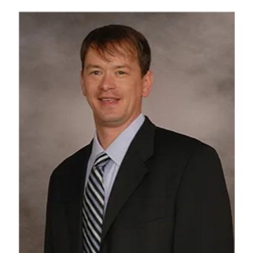 A man in a suit and striped tie smiling at the camera.