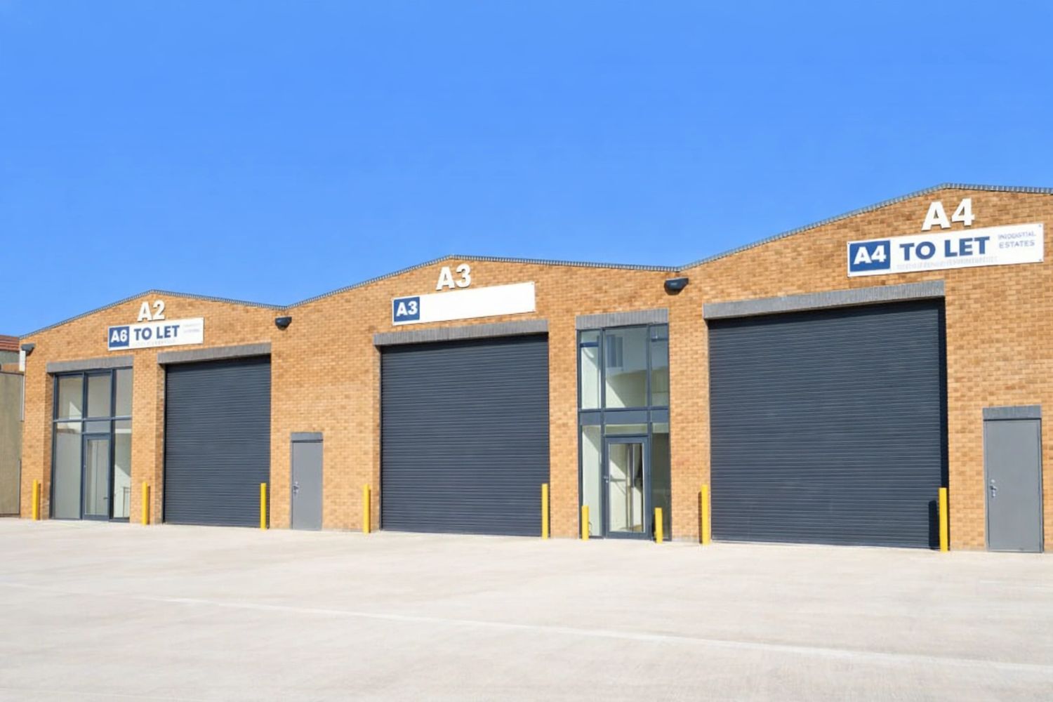 Row of modern industrial units with large roller doors and To Let signs.