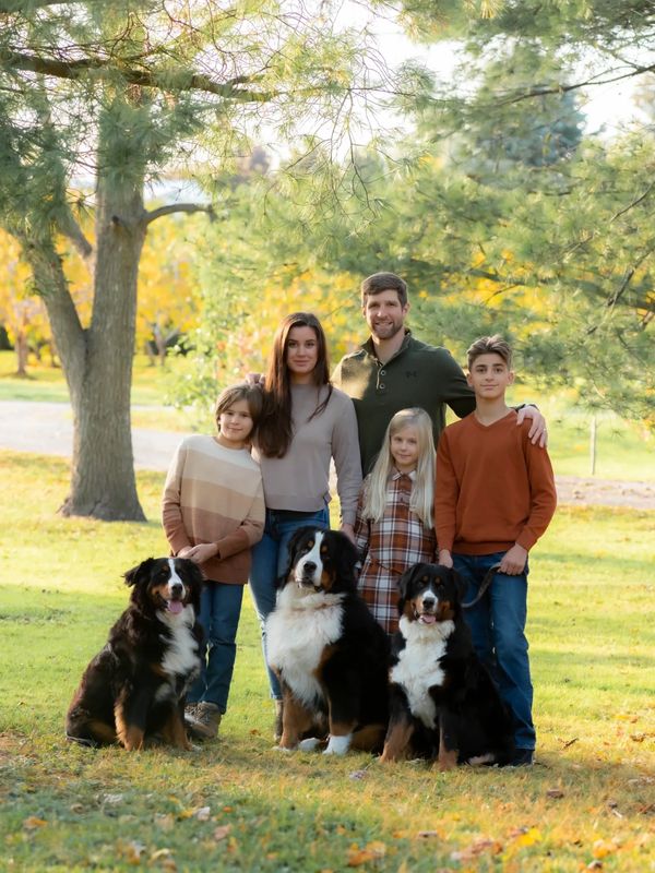 Family portrait with three dogs in a park.