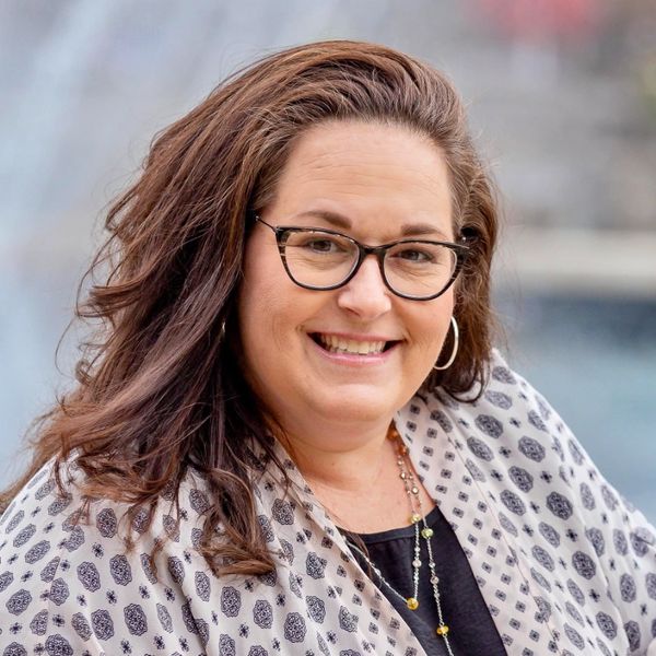Smiling woman with glasses and patterned shawl.