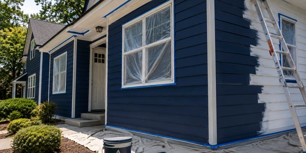 House exterior being painted dark blue with white trim.