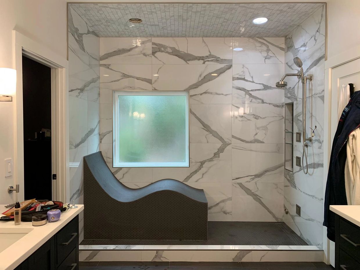 Modern bathroom with a sculptural bath seat and large marble tiles.