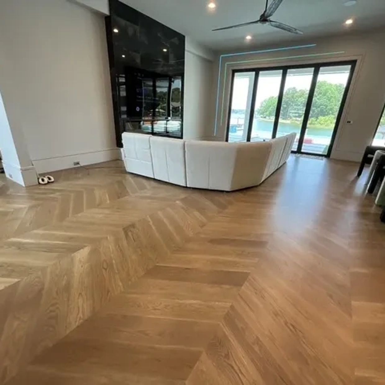 Modern living room with wooden herringbone floor and white sofa.