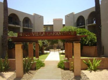 Entrance to Villa Lafayette with plants and beige buildings.
