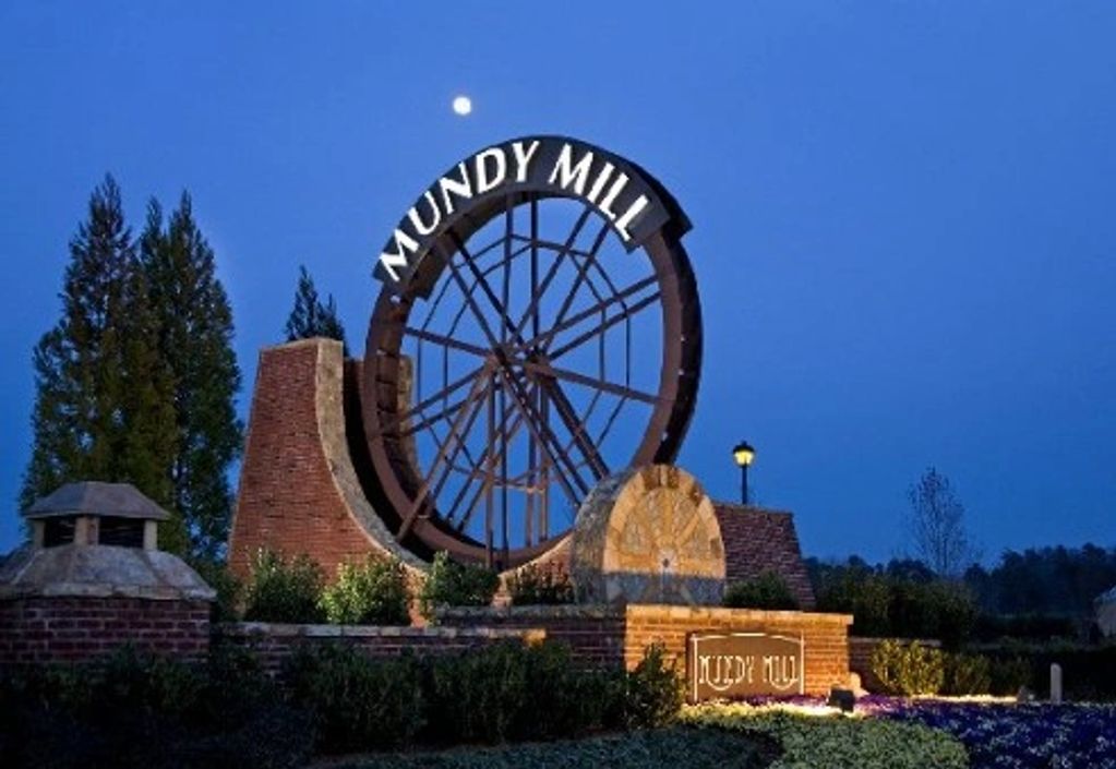 Large water wheel structure with 'Mundy Mill' sign at dusk.