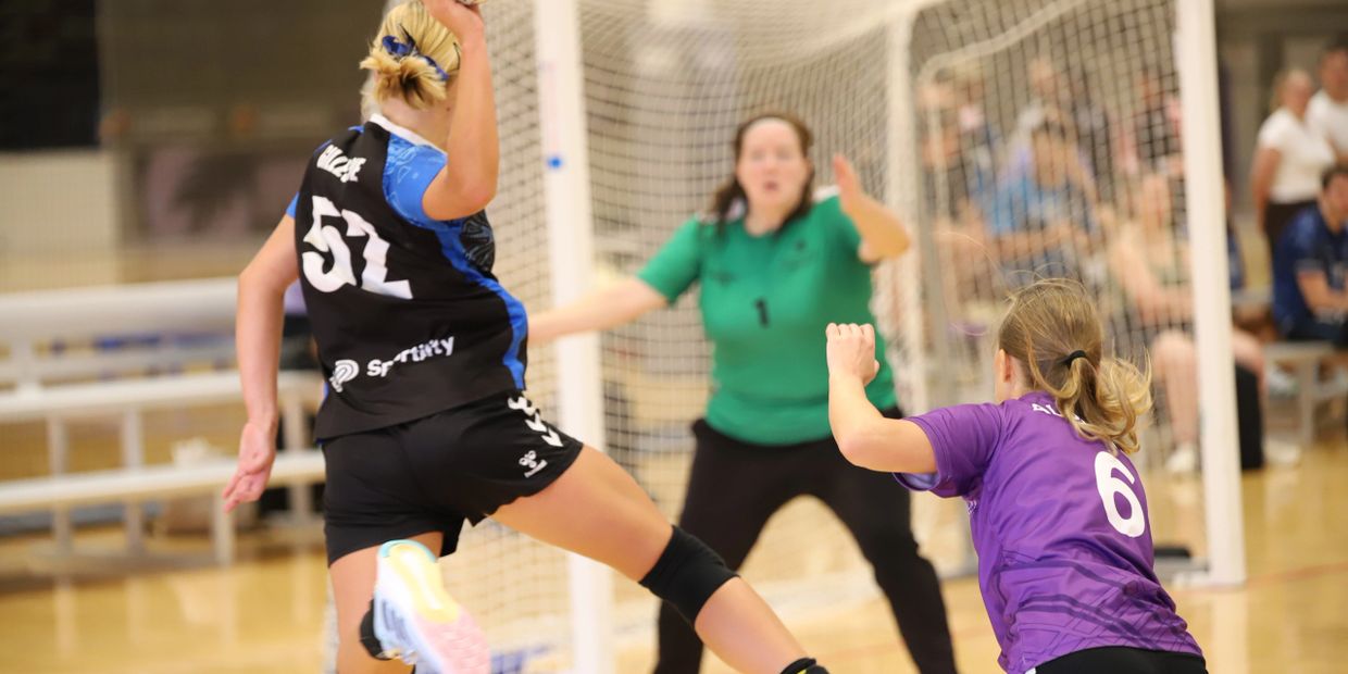 Female handball players in action near the goal during a match.
