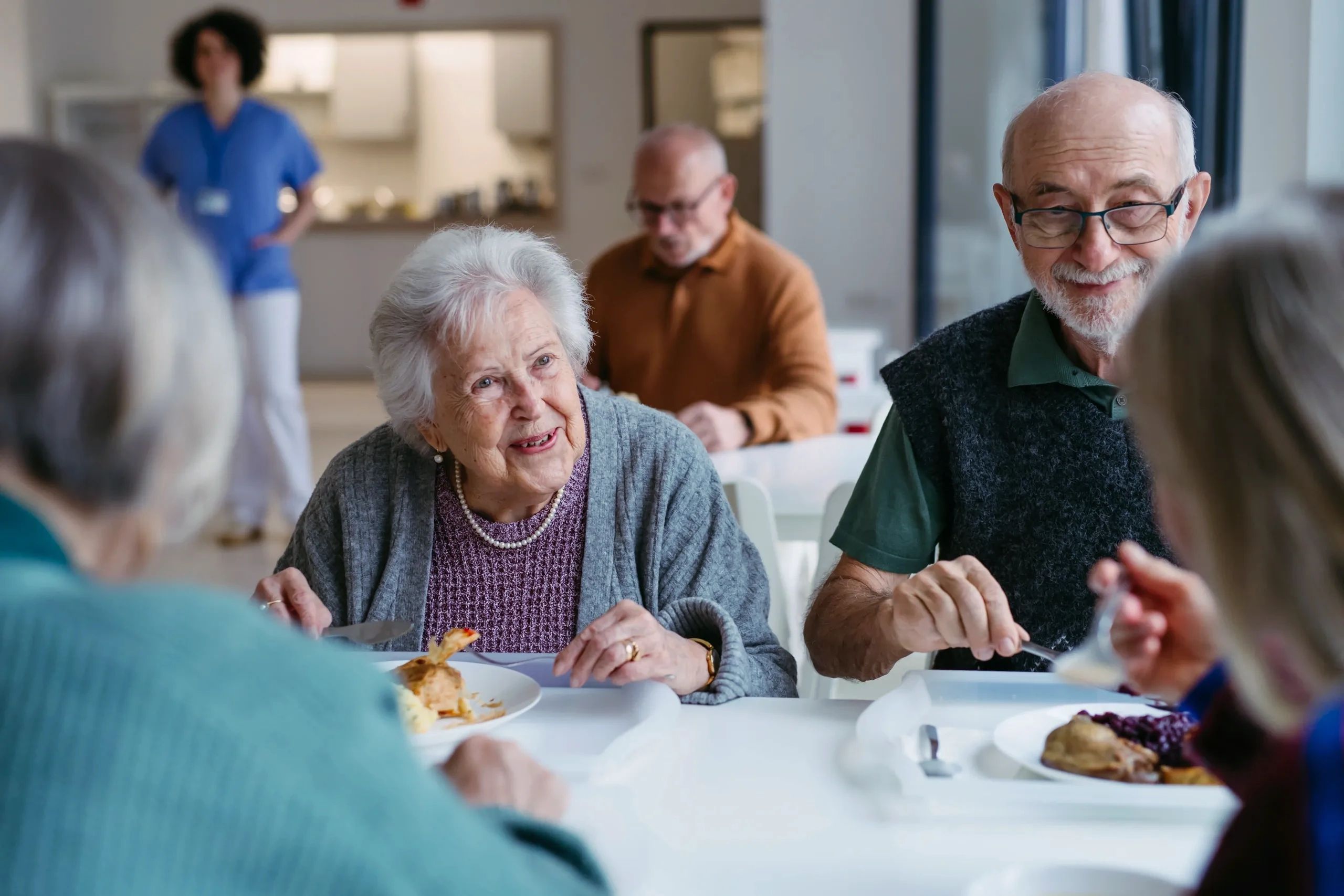 Elderly people enjoying a meal together in a communal setting.