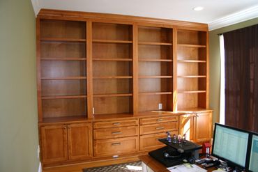 Empty wooden bookshelf with drawers and cabinets in a home office.