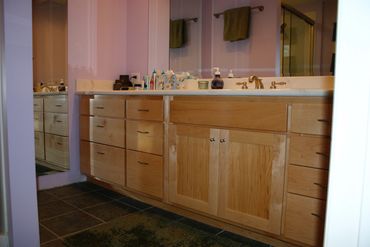 Maple bathroom vanity with sink and large mirror.