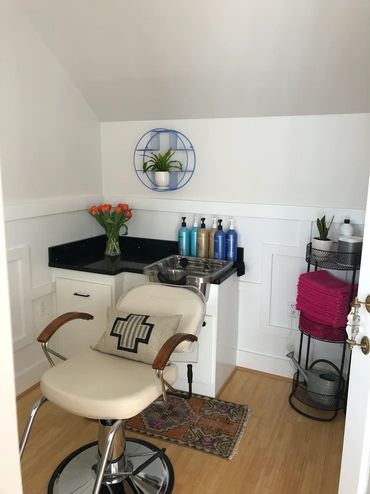 Cozy salon corner with a stylish chair, colorful products, and fresh flowers.
