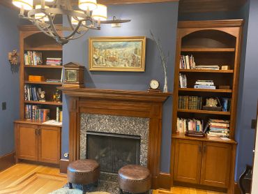 Cozy living room with wooden shelves and a fireplace.