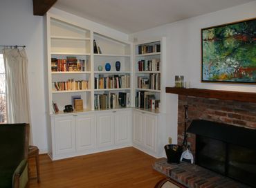 Cozy living room corner with white bookshelves and a brick fireplace.