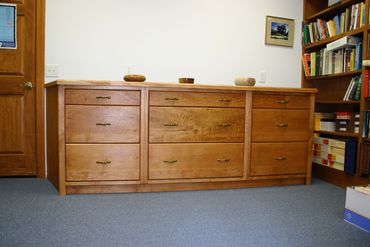 A wooden dresser with multiple drawers in an office setting.
