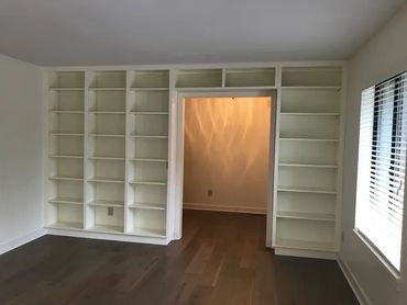 Empty room with built-in white shelves around a doorway.