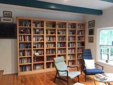 Cozy reading corner with wooden bookshelves and comfortable chairs.