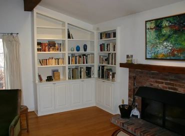 Cozy living room corner with built-in bookshelves and brick fireplace.