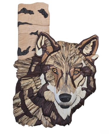 Wooden artwork of a Wolf, intently looking at you.  There is a birch tree trunk behind it.