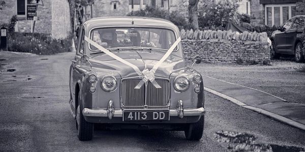 Vintage car decorated with ribbons, likely for a wedding.