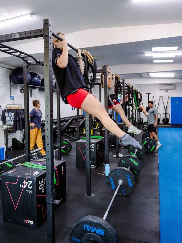 People exercising with pull-up bars and weights in a gym setting.