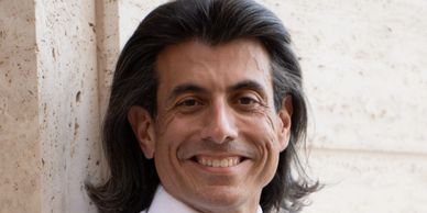 Man smiling with long dark hair.