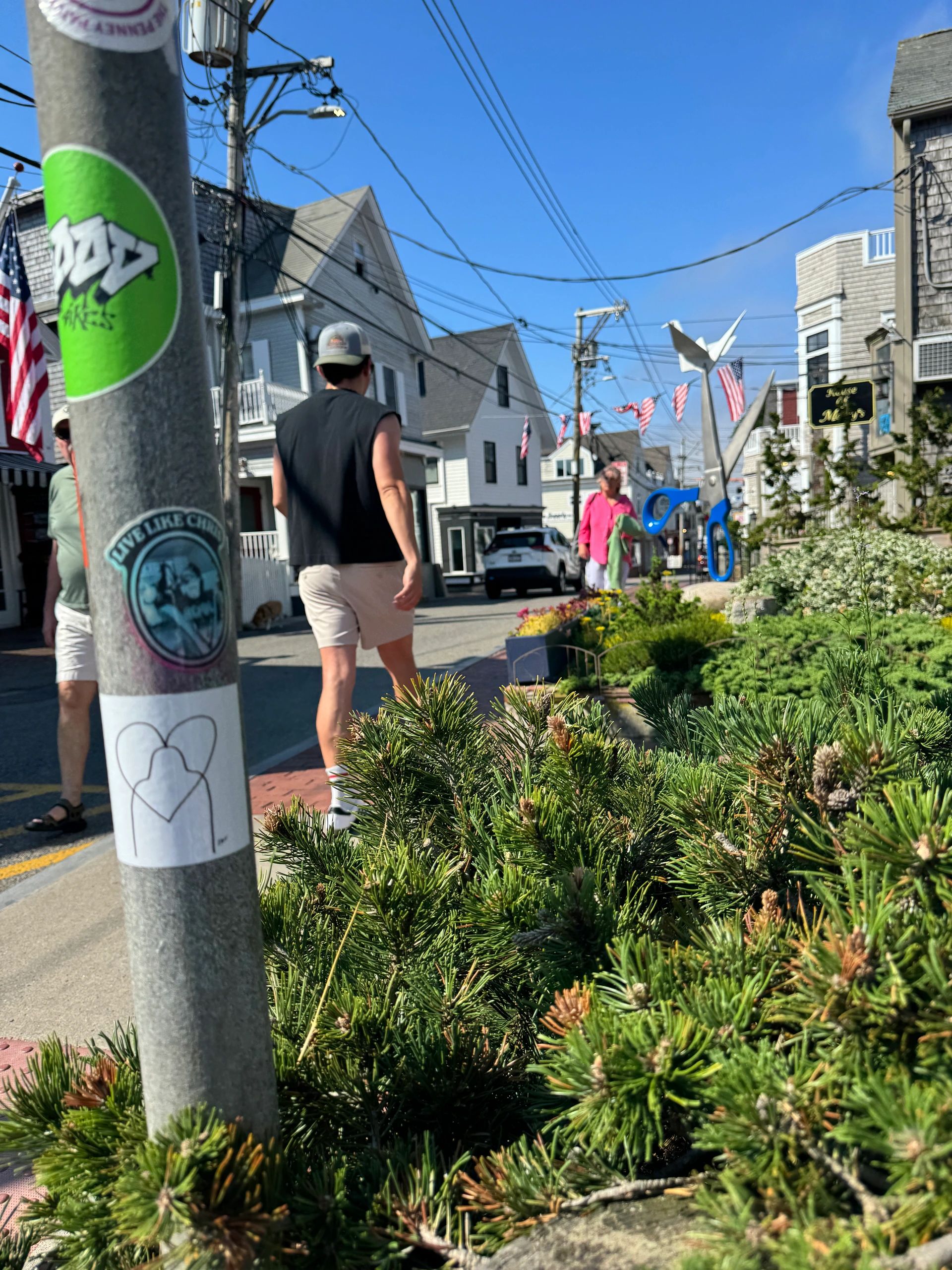 Street scene with people and large scissors sculpture.