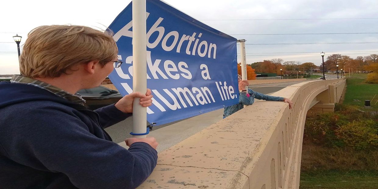 Voices for Life volunteers hold a pro-life banner to save lives and end abortion. 