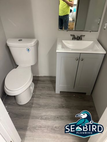 Small modern bathroom with toilet and sink, featuring gray flooring.