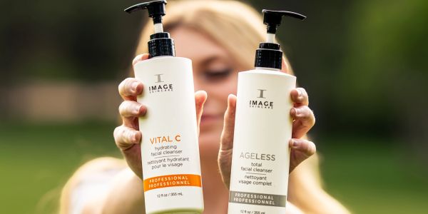A person holding IMAGE Skincare facial cleanser bottles.