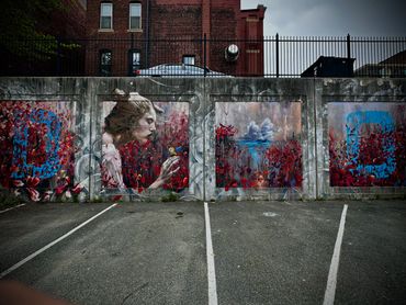 Street art featuring a woman and vibrant red foliage on a concrete wall in a parking lot.