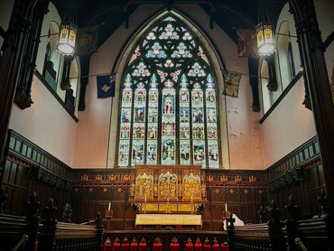 Ornate church altar with stained glass window and wooden paneling.