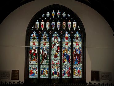 Intricate stained glass window depicting biblical figures inside a church.