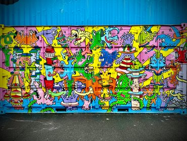 Colorful graffiti of whimsical characters painted on a container wall.
