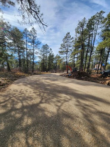 A newly paved road winding through a forested area with construction equipment.