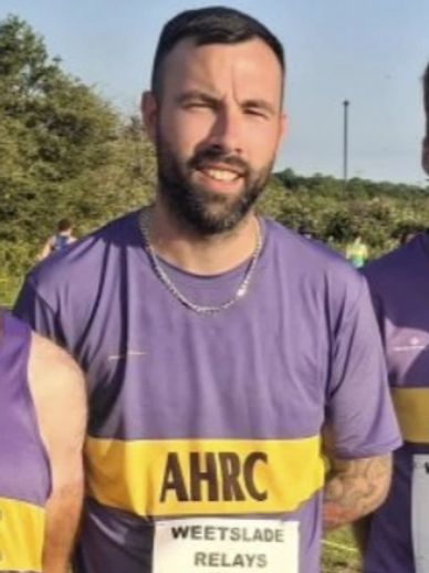 Man in purple running shirt at outdoor event.