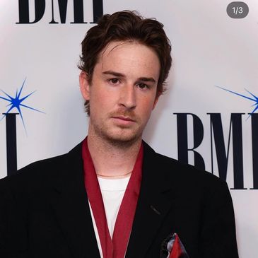 Young man in a black blazer with red scarf at a BMI event.