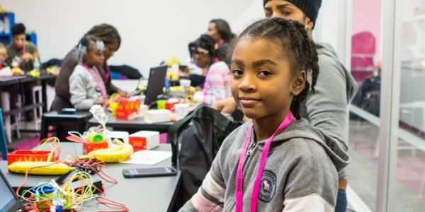 Young girl in a classroom with electronic kits and laptops.