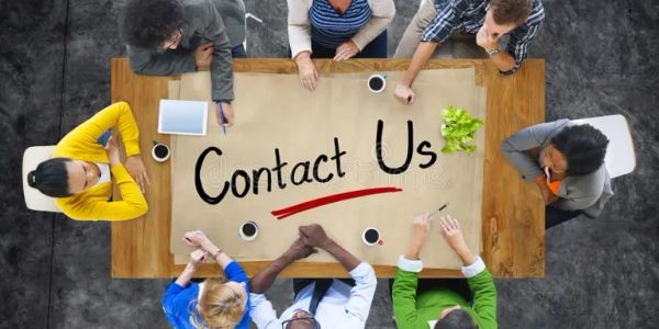 Diverse team gathered around a table with 'Contact Us' written on paper.