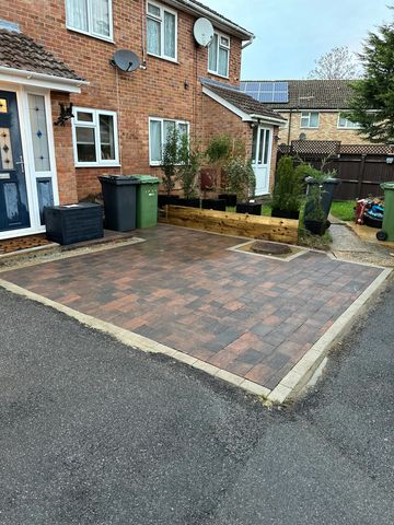 Brick house with paved driveway and garden plants in pots.