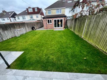 A neat backyard with green lawn and small soccer goals.