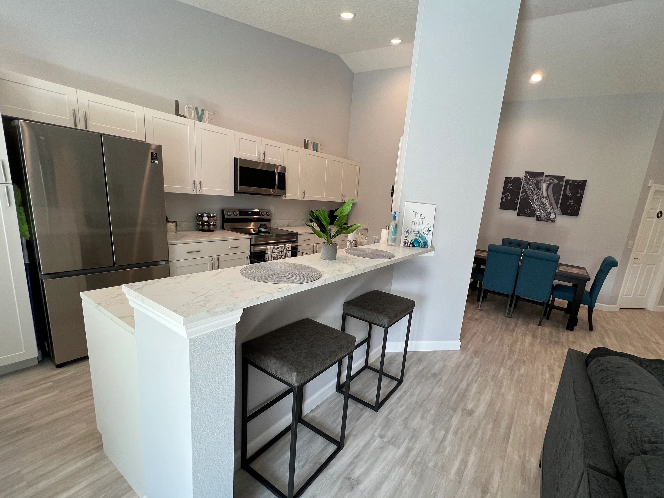 An overview of the kitchen area with stainless steel refrigerator, stove, and microwave.