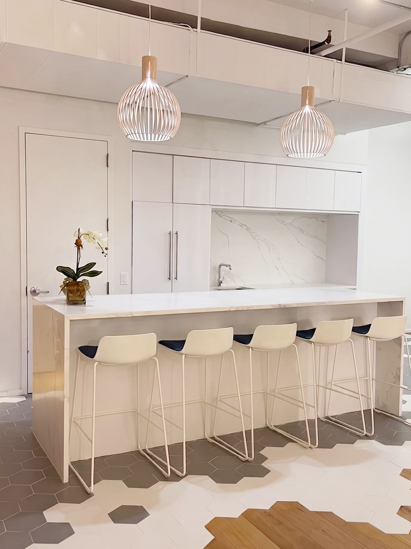Modern kitchen with island and hexagonal tile floor blending into wood.