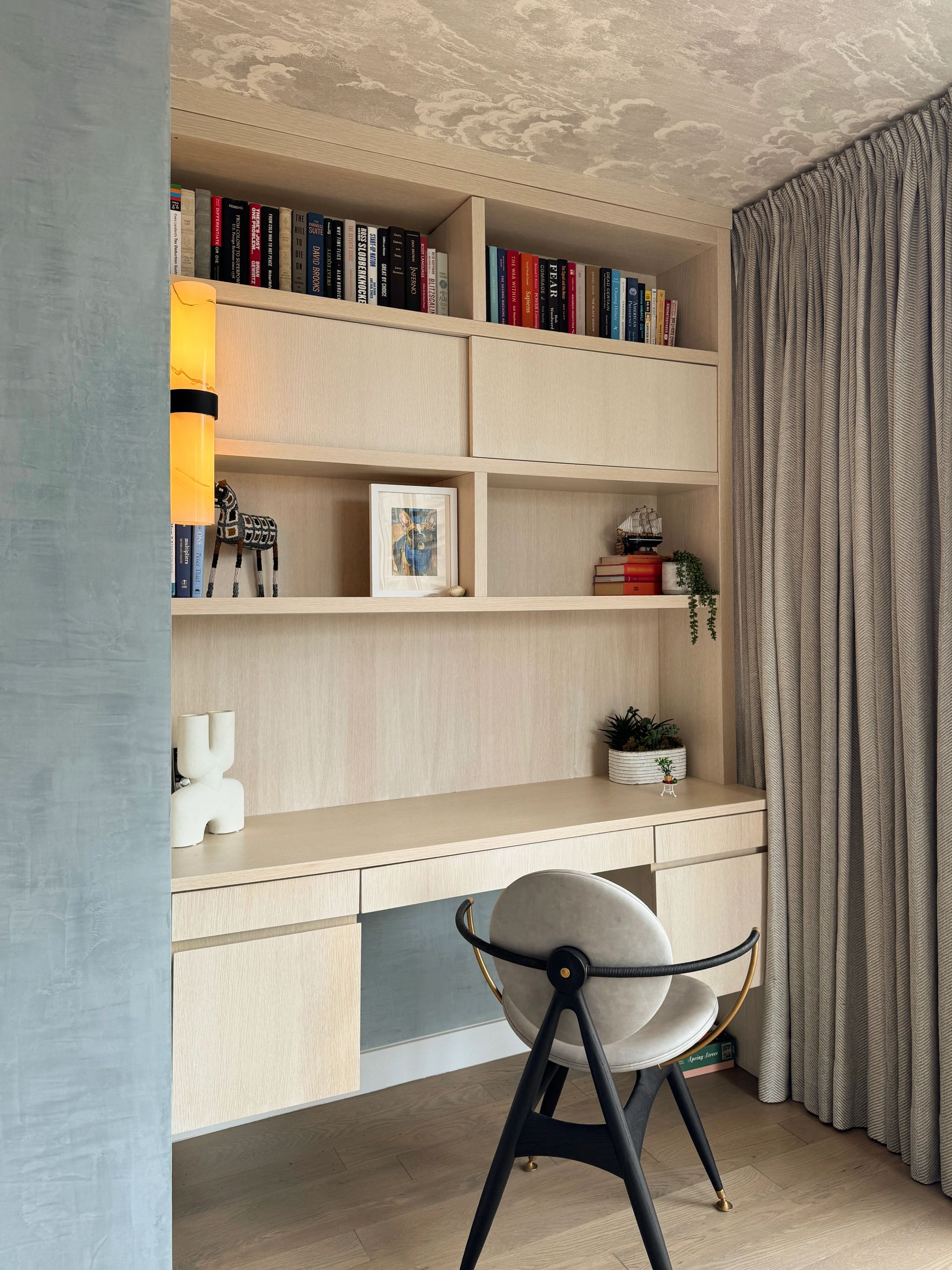 Modern wooden study desk with decorative shelves and cozy chair.